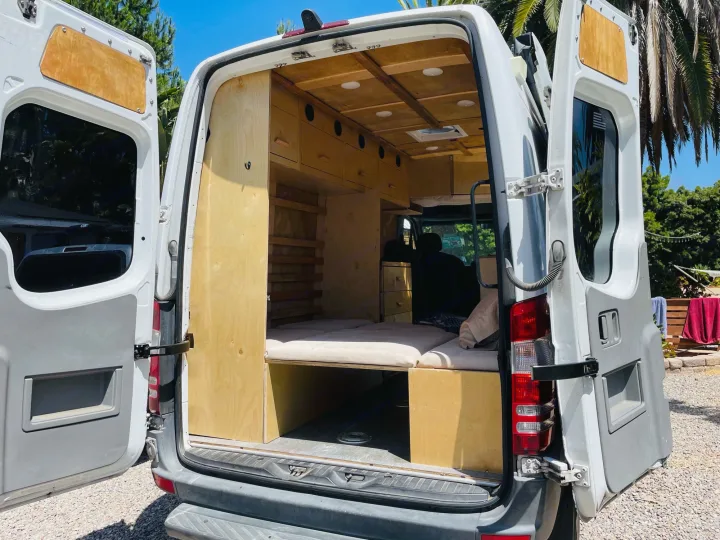 Custom wood interior of a camper van, ideal for rv rental or adventure. Features bed, storage, and cozy setup.. Dodge Sprinter Van 2007