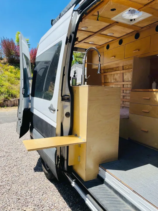 RV rental: Custom Sprinter van conversion featuring a clever exterior table, sink, and warm wood interior.. Dodge Sprinter Van 2007