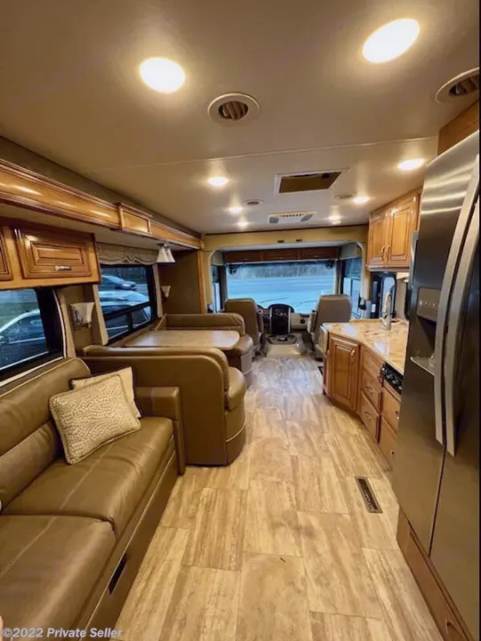 Spacious RV rental interior featuring a full kitchen, comfortable seating, and dining area, leading to the driver's cockpit.. Thor Challenger 2017