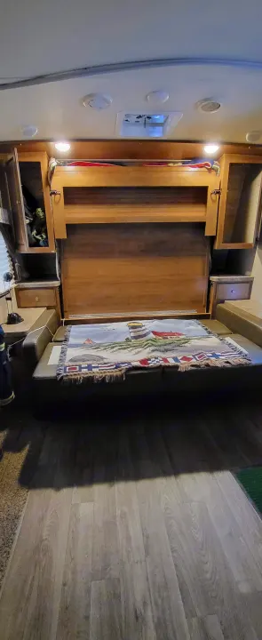 RV rental interior shows a space-saving murphy bed, sofa, and storage in a compact RV setup.. Forest River Flagstaff Micro Lite 2018