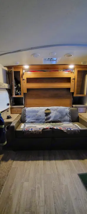 RV rental interior featuring a versatile sofa-bed, overhead cabinets, and wood-look flooring.. Forest River Flagstaff Micro Lite 2018