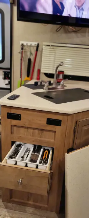 Efficient rv rental kitchen: sink, counter, and an open drawer neatly showing organized utensils & tools.. Forest River Flagstaff Micro Lite 2018