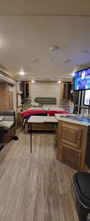 Inside an rv rental, a compact yet functional interior includes a comfortable bed, small kitchen, dinette, and entertainment setup.. Forest River Flagstaff Micro Lite 2018