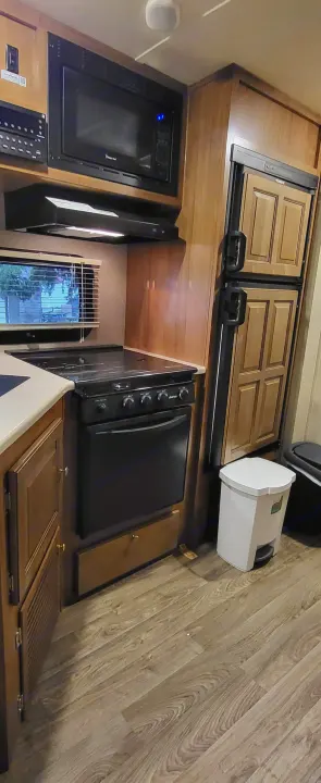 This compact RV rental kitchen features a microwave, range, oven, and refrigerator, perfect for travel cooking.. Forest River Flagstaff Micro Lite 2018