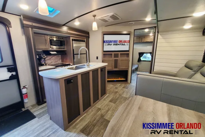 Inside this modern RV rental, find a spacious kitchen island, comfortable living area with TV & fireplace.. Crossroads Sunset Trail 2022
