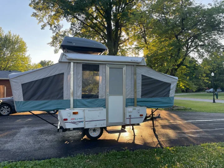 Pop-up camper RV rental displayed with Thule cargo box. Ideal for outdoor adventures & easy travel.. Coleman Destiny Taos 1996