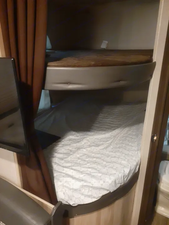 Cozy RV rental interior featuring two bunk beds with a TV mounted by the bottom bunk, offering compact sleeping space.. Forest River Coachmen Catalina Summit 2020
