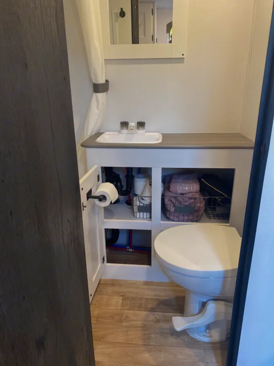 Inside an RV rental bathroom, featuring a compact toilet, sink vanity, and practical under-cabinet storage.. Keystone RV Hideout 2022
