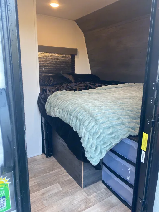 RV rental: A cozy, compact bedroom interior with a bed, plush blue blanket, wood floors, and under-bed storage drawers.. Keystone RV Hideout 2022