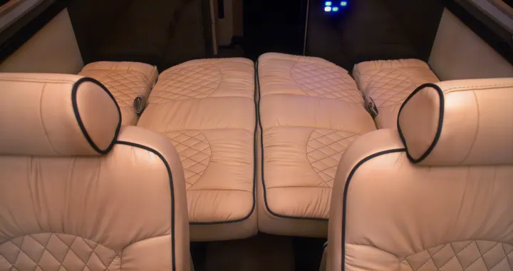 Luxurious RV rental interior features plush white leather seats, some converted into comfortable sleeping areas for travel.. Ultimate Toys Ultimate Coach 2023