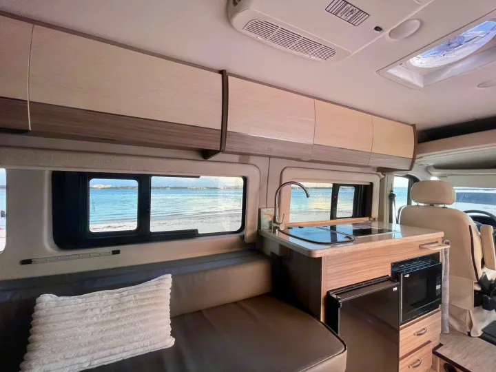 Cozy rv rental interior with kitchen, seating, and ocean view from the window. Perfect for a beach getaway.. Entegra Coach Ethos 2021