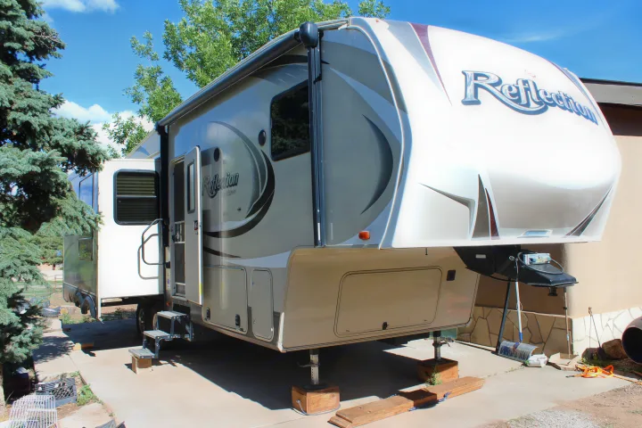 A large, white and beige Grand Design Reflection fifth-wheel RV rental, perfectly set up and parked outdoors on a sunny day.. Grand Design Reflection 2015