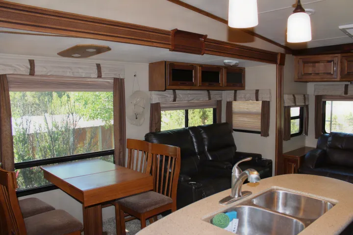 Spacious rv rental interior featuring a dining area, leather living room recliners, and kitchen with sink.. Grand Design Reflection 2015