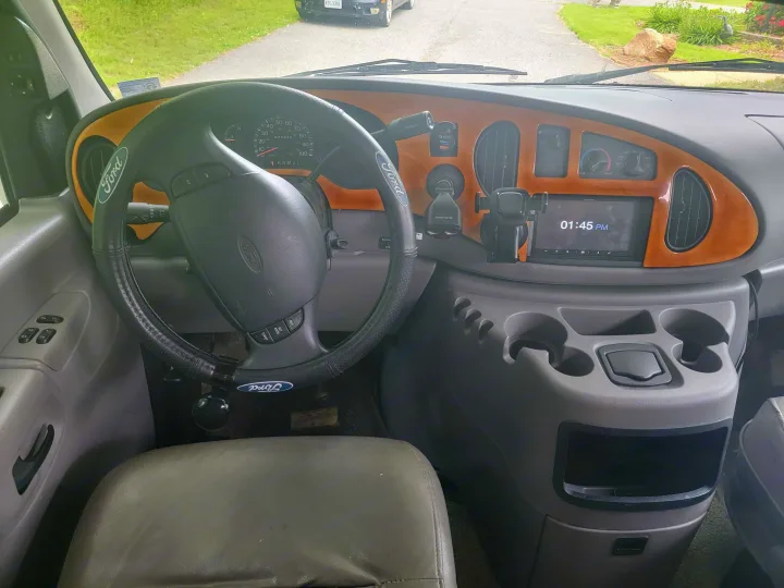 Driver's view of an RV rental: Ford van dashboard with steering wheel, gauges, and Alpine stereo.. Coachmen Santara 2003