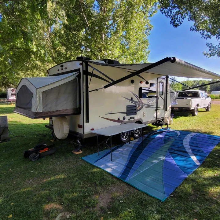 Spacious RV rental set up for camping, featuring an extended pop-out, large awning, and outdoor mat for a comfortable stay.. Forest River Rockwood Roo 2017