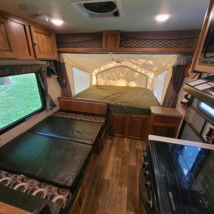 Bright RV rental interior with pop-out bed, convertible dinette, full kitchen, and wood floors.. Forest River Rockwood Roo 2017