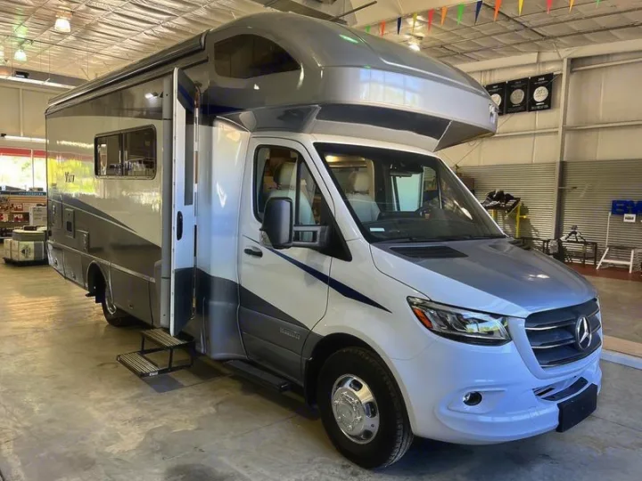 Spacious white & gray RV rental with steps, likely a Mercedes Sprinter-based motorhome, displayed indoors.. Winnebago View 2023