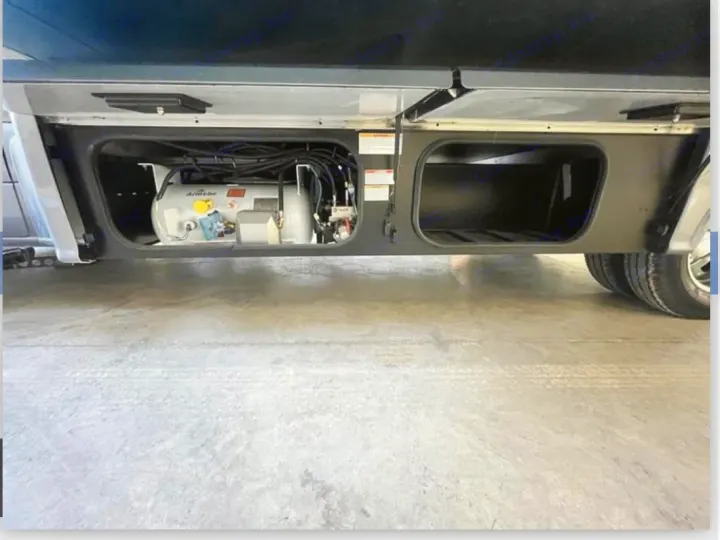 RV rental underside view. Air tank for suspension/leveling in one bay; spacious empty storage compartment beside it.. Winnebago View 2023