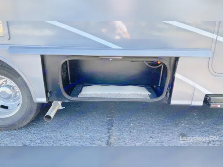 This RV rental features an open exterior storage compartment with a mat inside & exhaust pipe below, perfect for your gear.. Winnebago View 2023