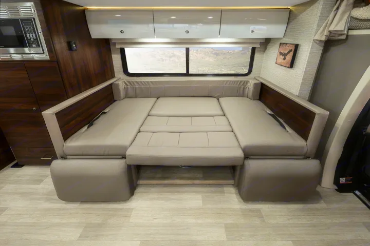 Versatile RV rental interior: A compact dinette easily converts to a comfortable bed, blending style and practical space.. Winnebago View 2023