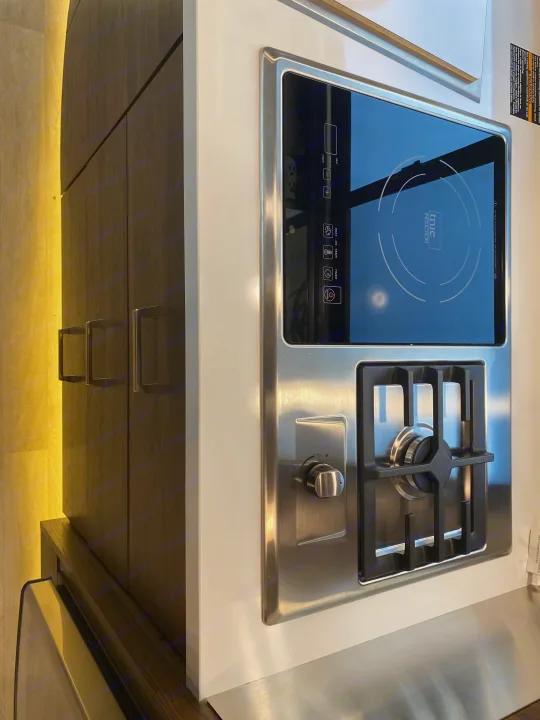 Modern RV rental kitchen featuring a compact induction cooktop, gas burner, and illuminated cabinets.. Winnebago View 2023