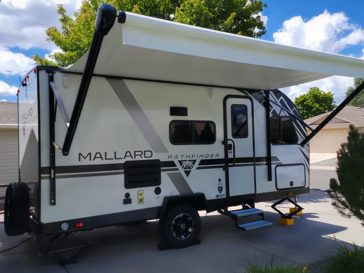 White Mallard Pathfinder RV rental with awning extended, parked in a driveway on a sunny day.. Heartland RVs Mallard Pathfinder 2022