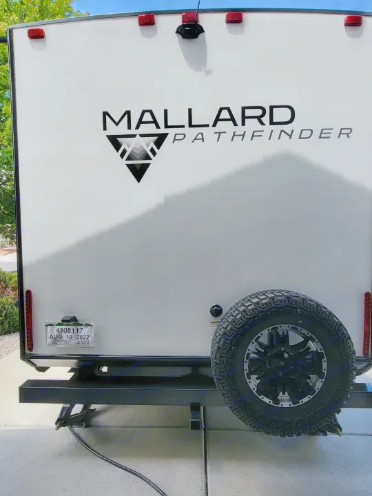 Rear view of a white Mallard Pathfinder RV rental with a spare tire, taillights, and Colorado registration.. Heartland RVs Mallard Pathfinder 2022