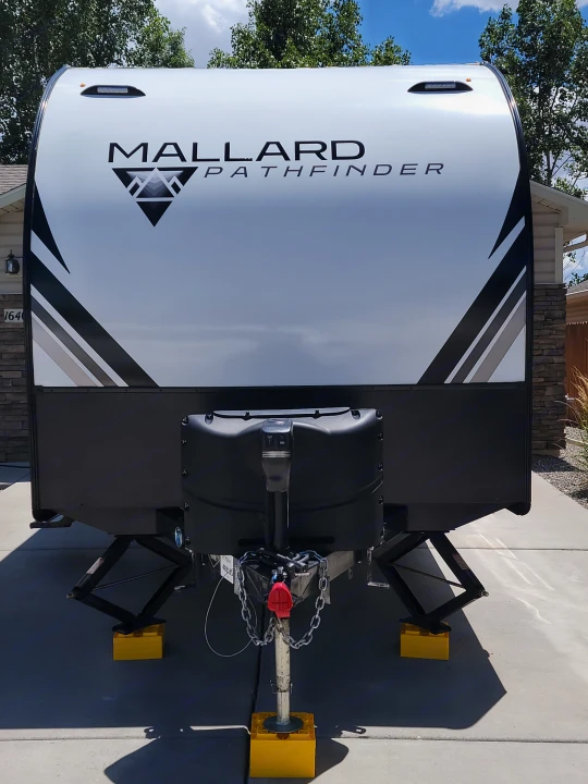 RV rental: Front view of a white Mallard Pathfinder travel trailer, with its hitch, jacks, and yellow leveling blocks visible.. Heartland RVs Mallard Pathfinder 2022