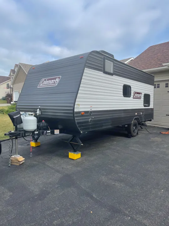 A Coleman travel trailer, common for an RV rental, is parked on a driveway. Ready for camping trips.. Dutchmen Coleman Lantern LT 2021