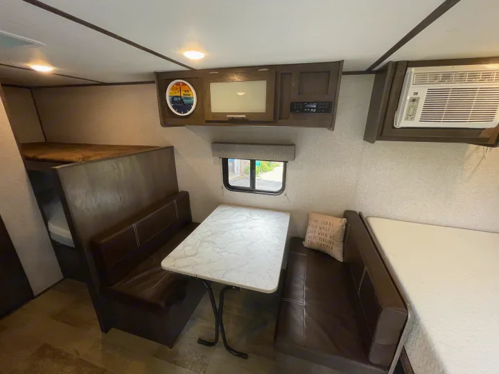 This RV rental interior features a cozy dinette, bunk beds, AC unit, and entertainment center for comfortable travels.. Dutchmen Coleman Lantern LT 2021