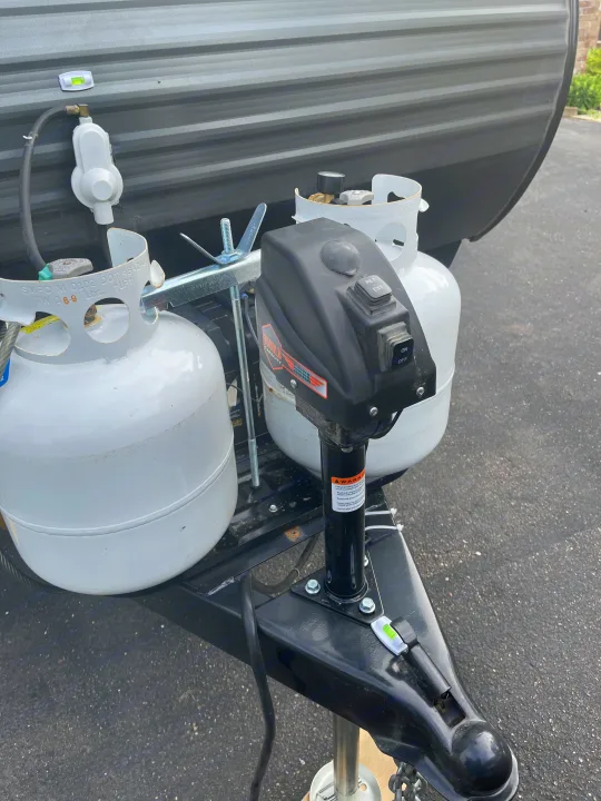 RV rental's front features: propane tanks, electric tongue jack, and leveling indicators ready for travel.. Dutchmen Coleman Lantern LT 2021