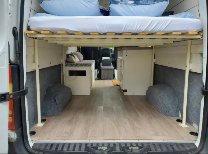 Spacious camper van interior, ideal for RV rental. Raised bed, under-bed storage, and compact kitchen offer comfortable mobile living.. Mercedes-Benz Sprinter RV Motorhome Campervan 2016
