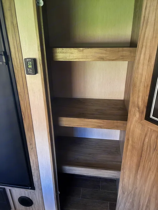 RV rental: Interior showing empty pantry shelves, refrigerator, and a digital thermostat displaying 96 degrees.. Forest River Cherokee Alpha Wolf 2021