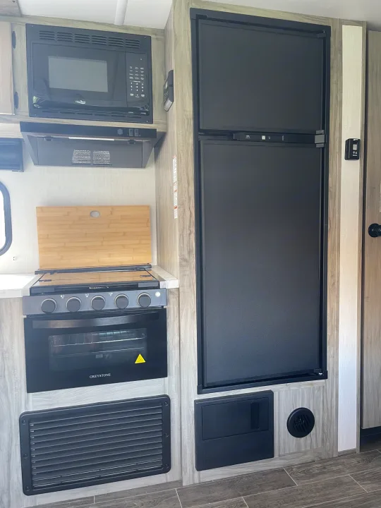 RV rental kitchen: compact, yet fully equipped with microwave, stove/oven, and tall refrigerator.. Forest River Cherokee Alpha Wolf 2021