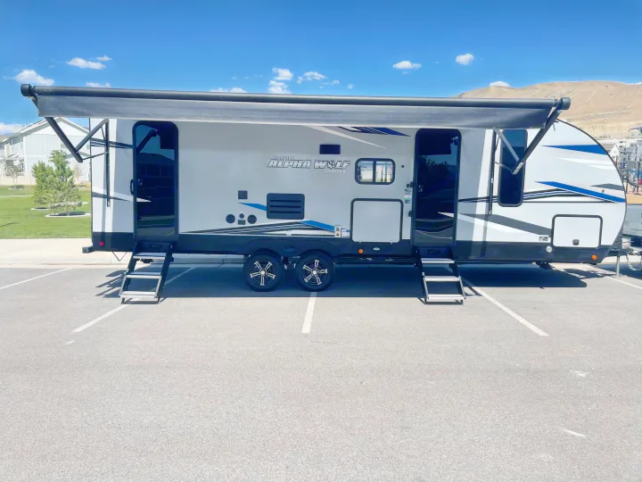 Modern Alpha Wolf RV rental with extended awning & steps in a sunny parking lot, ideal for your next outdoor adventure.. Forest River Cherokee Alpha Wolf 2021
