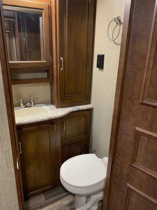 RV rental bathroom interior: Features a white toilet, sink with vanity, wood cabinets, and a mirror.. Other Outback 2017