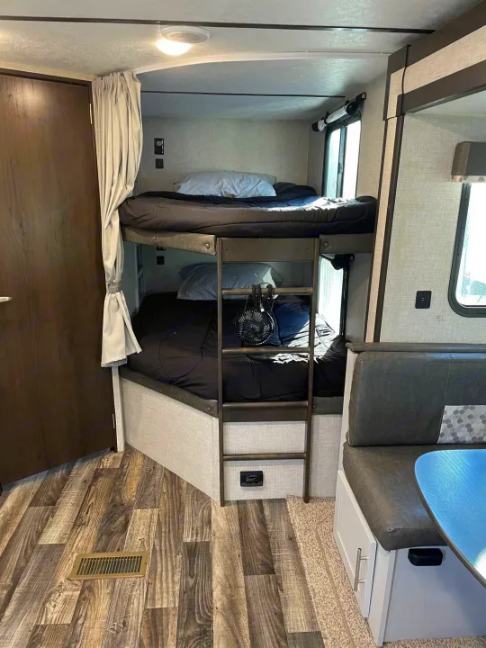 RV rental interior: cozy bunk beds with ladder, dinette seating, and wood-look flooring. Ideal for family adventures.. Keystone Bullet 2020