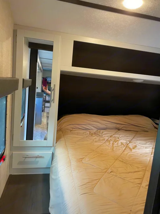 Cozy RV rental bedroom with comfortable bed, overhead bunk, and mirrored cabinet.. Keystone Bullet 2020