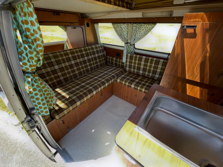 Cozy RV rental interior with plaid seating, wood paneling, polka dot curtains, and kitchen sink. Ready for adventure!. Volkswagen westfalia 1976