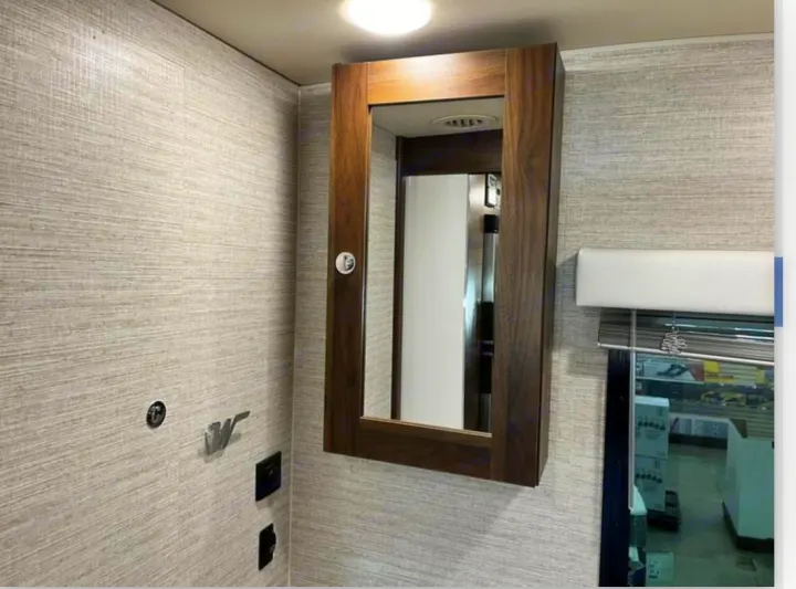 RV rental bathroom: a modern mirrored medicine cabinet, light textured walls, and a window with blinds.. Winnebago View 2022