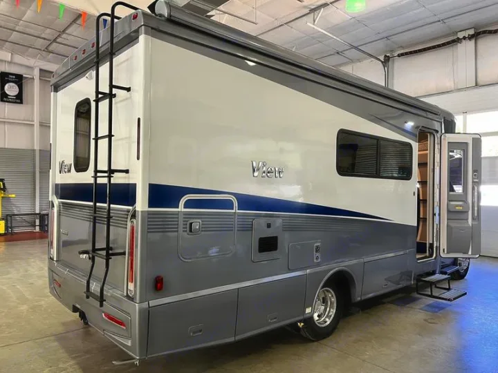 This spacious grey and white RV, perfect for rv rental, features an extended ladder, an awning, and open entry steps for easy access.. Winnebago View 2022