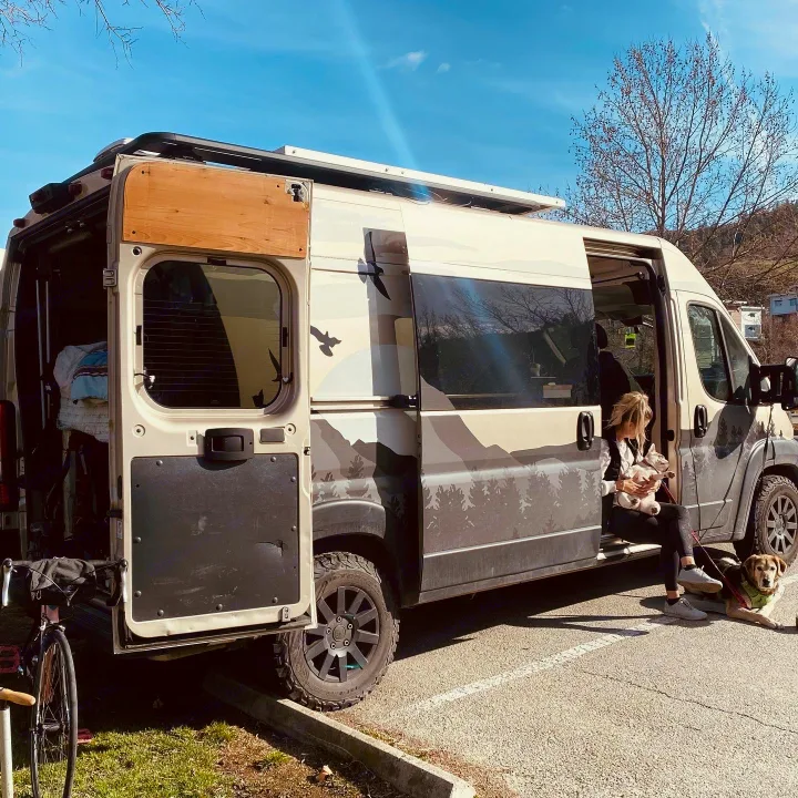 Woman and dogs relax by their personalized camper van, an ideal RV rental for pet-friendly adventures and road trips.. Dodge Ram 1500 2020