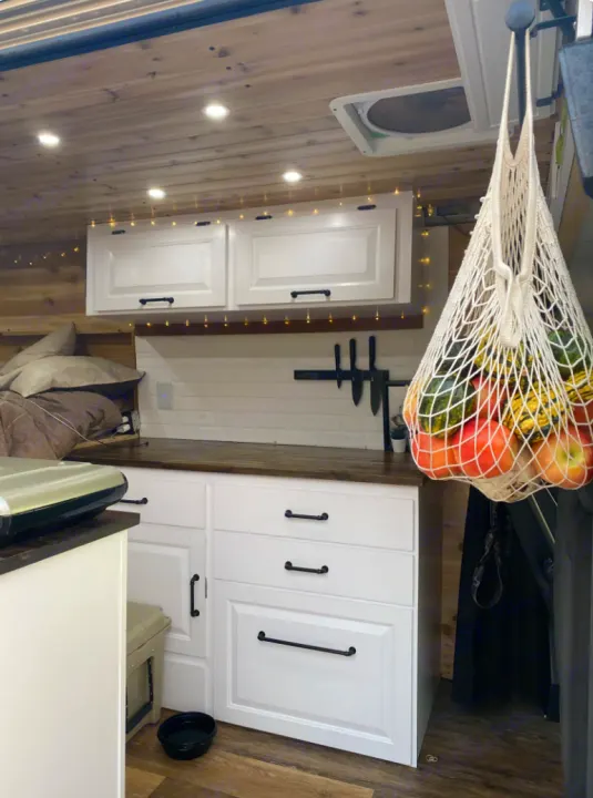 Cozy RV rental interior, showing a fully equipped compact kitchen with storage and fresh produce. Perfect for mobile living.. Dodge Ram 1500 2020