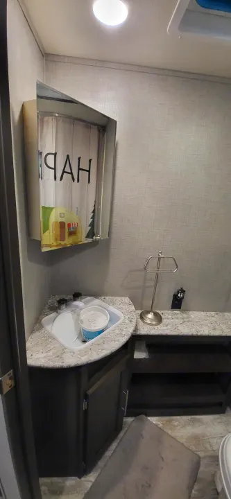 Inside an RV rental: a well-lit interior showing a sink, towel bar, dark cabinets, and a 'HAPPY' decor box.. Crossroads RV Zinger Lite 2020