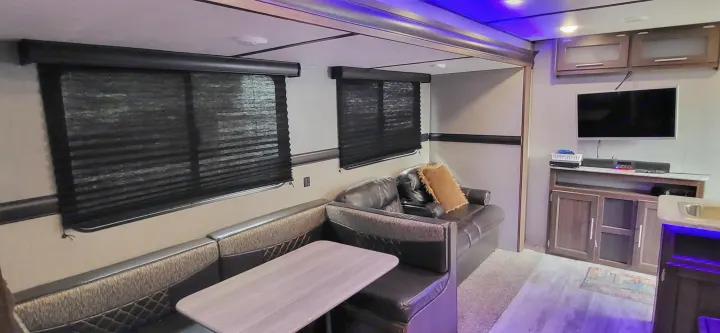 Cozy RV rental interior: Features a booth dinette, sofa seating, TV entertainment, and ambient blue lighting for comfortable travel.. Crossroads RV Zinger Lite 2020