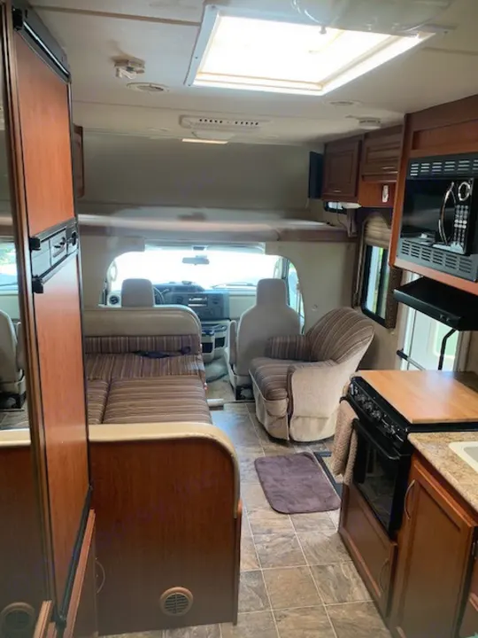 Spacious RV rental interior with kitchen (microwave, stove), dinette, and driver's cab area visible. Ready for your adventure!. Four Winds Four Winds Motorhome 2011