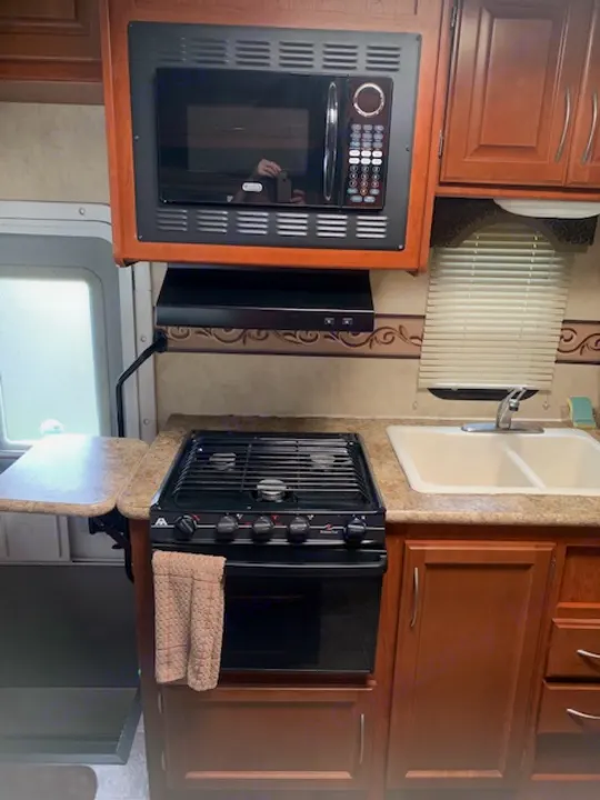 This RV rental kitchen offers a microwave, stovetop, and sink. All essential cooking amenities for your journey.. Four Winds Four Winds Motorhome 2011