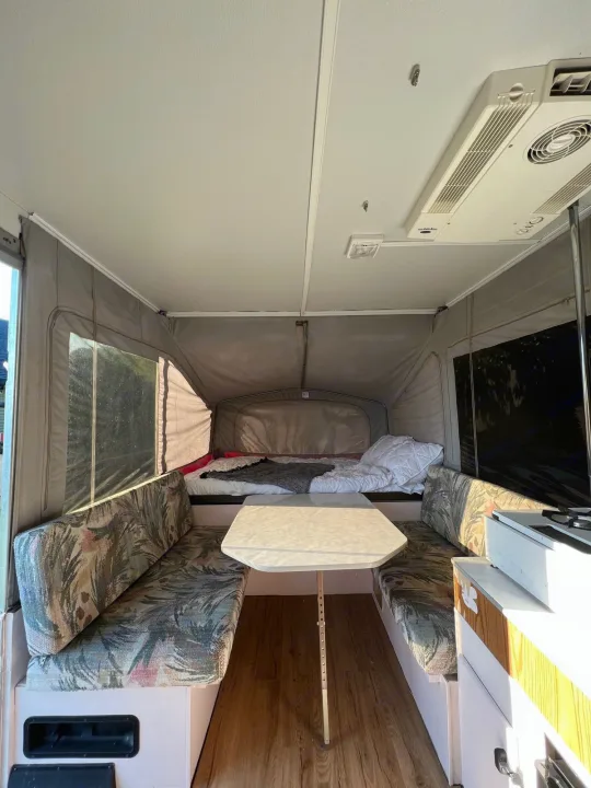 Cozy interior of an RV rental pop-up camper, featuring bed, dinette, and mini-kitchen.. Jayco Eagle 1996