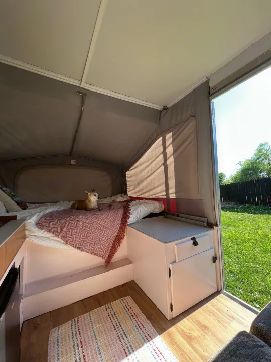 Cozy RV rental interior shows a bed with a dog, ready for travel adventures and outdoor living.. Jayco Eagle 1996