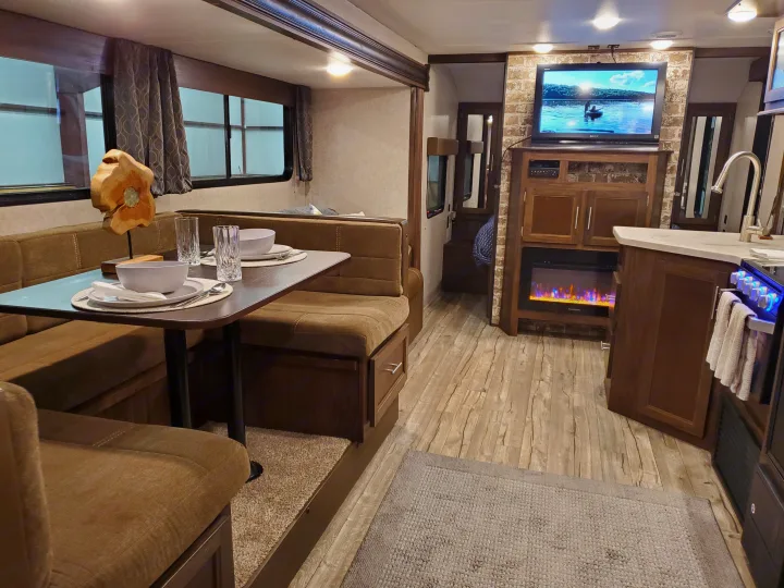 RV rental interior: dining booth, full kitchen, living area with TV & electric fireplace. Wood floors, modern and inviting.. Forest River Cherokee Grey Wolf 2018